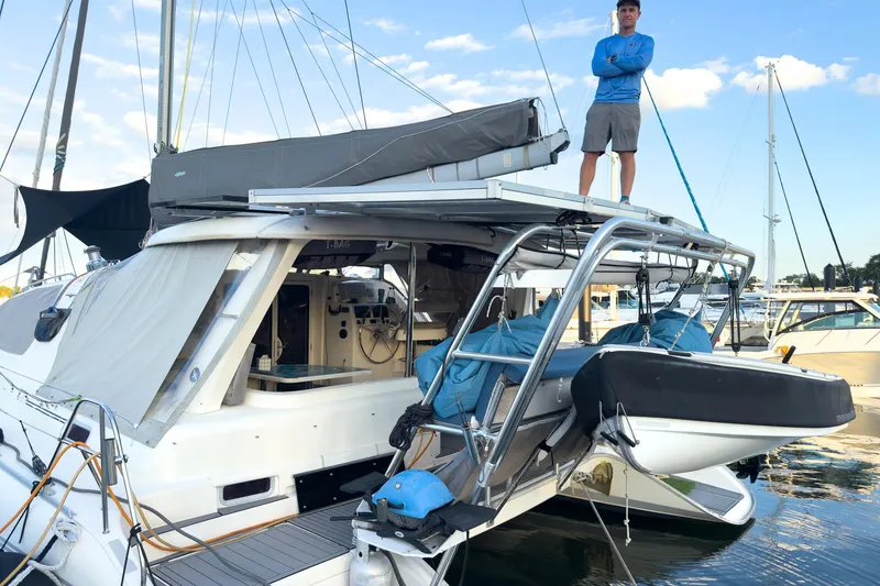 Slide: The Image of Man standing on 2006 Leopard 43 catamaran at marina, with dinghy and clear sky. - 3