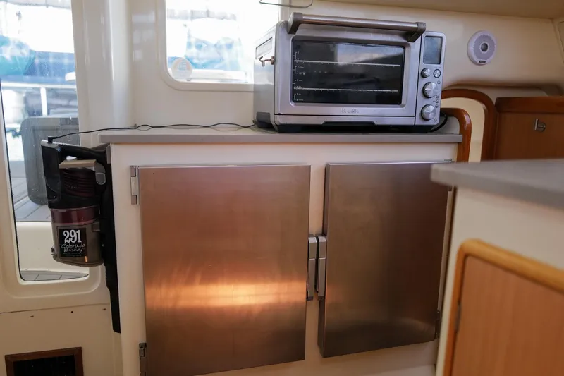 Slide: The Image of Compact kitchen area in a 2006 Leopard 43 yacht with stainless steel cabinets and a countertop oven. - 32