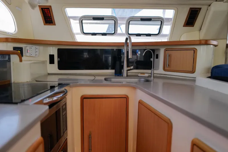 Slide: The Image of Modern kitchen interior of a 2006 Leopard 43 yacht, featuring sleek countertops and wooden cabinetry. - 34