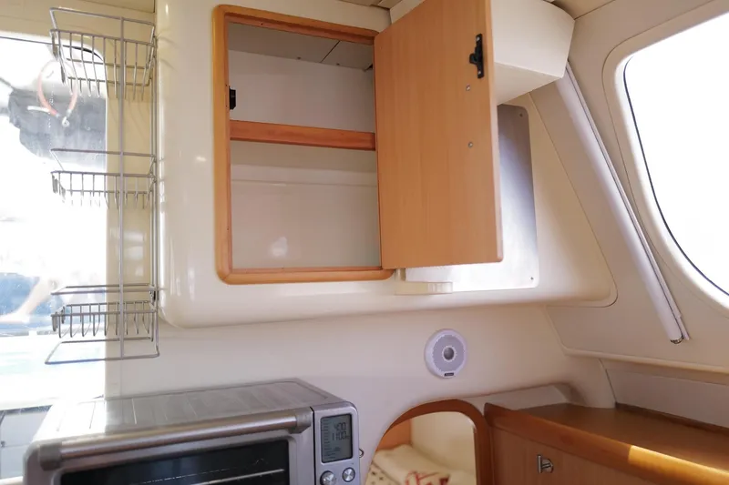 Slide: The Image of Interior of a 2006 Leopard 43 yacht with open wooden cabinet and kitchen appliances. - 44