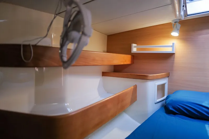 Slide: The Image of Cozy cabin interior of 2006 Leopard 43 yacht with wooden shelves and blue bedding. - 51