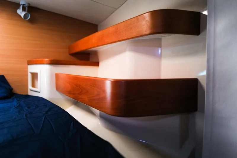 Slide: The Image of Interior of a 2006 Leopard 43 yacht with wooden shelves and a blue bedspread. - 53