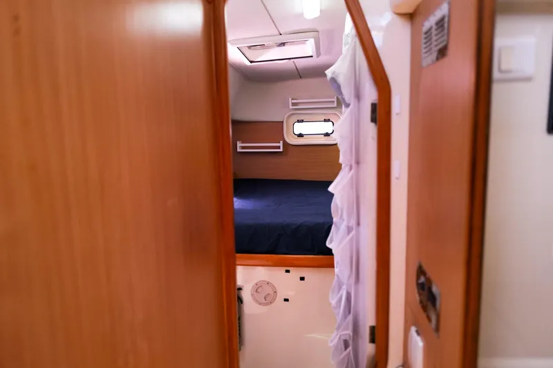 Slide: The Image of Cozy cabin interior of a 2006 Leopard 43 yacht, featuring a comfortable bed and wooden finish. - 54