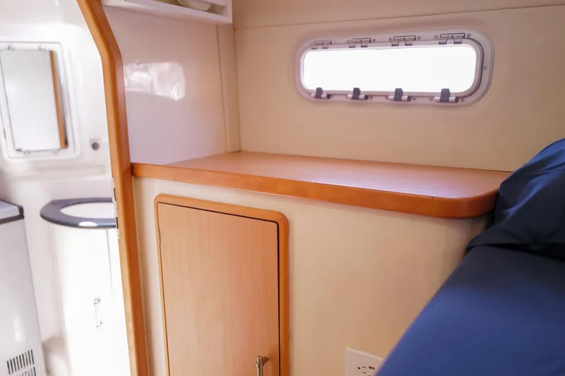 Slide: The Image of Interior of a 2006 Leopard 43 yacht cabin with wooden cabinetry and a small window. - 73