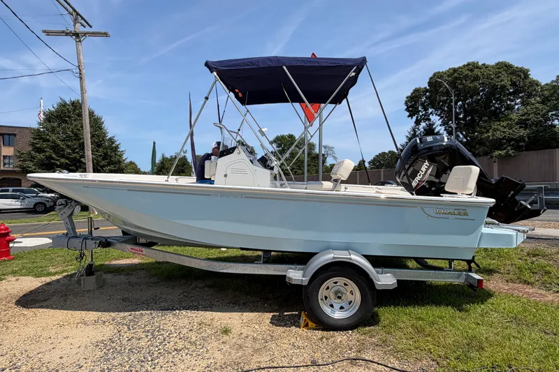 Slide: The Image of A 2027 Boston Whaler 170 Montauk on a trailer. It features a blue canopy. - 1