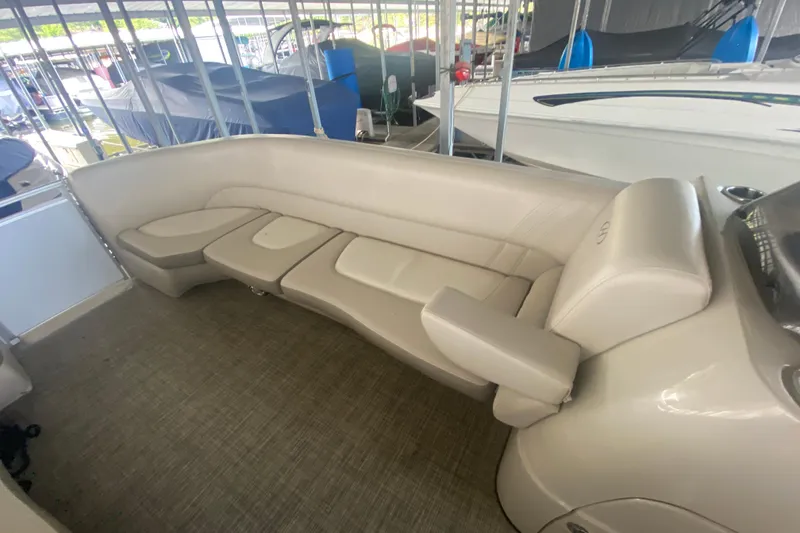 Slide: The Image of 2018 Harris Solstice 240 boat interior with beige seating and armrest in a marina setting. - 16