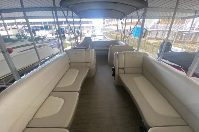 Slide: The Image of 2018 Harris Solstice 240 pontoon boat interior with beige seating and canopy in marina. - 19