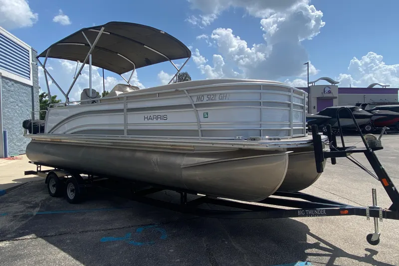 Slide: The Image of 2018 Harris Solstice 240 pontoon boat on trailer, parked outdoors under a cloudy sky. - 6