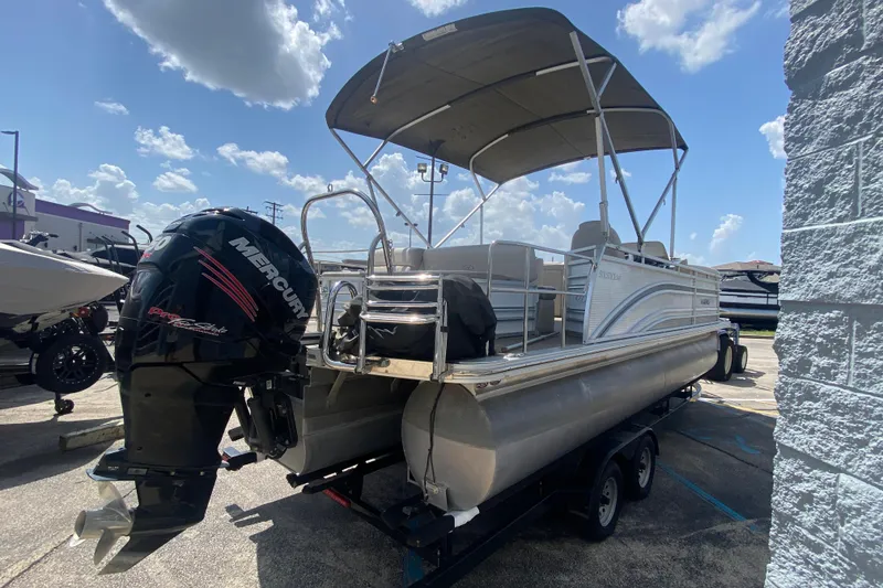 Slide: The Image of 2018 Harris Solstice 240 pontoon boat with Mercury engine, parked outdoors under a cloudy sky. - 4