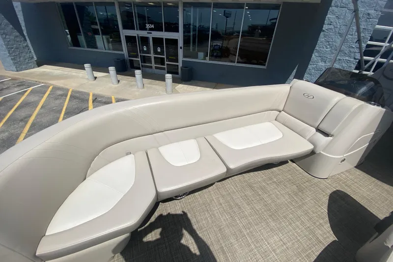 Slide: The Image of 2018 Harris Solstice 240 boat interior with beige seating, parked outside a building. - 8