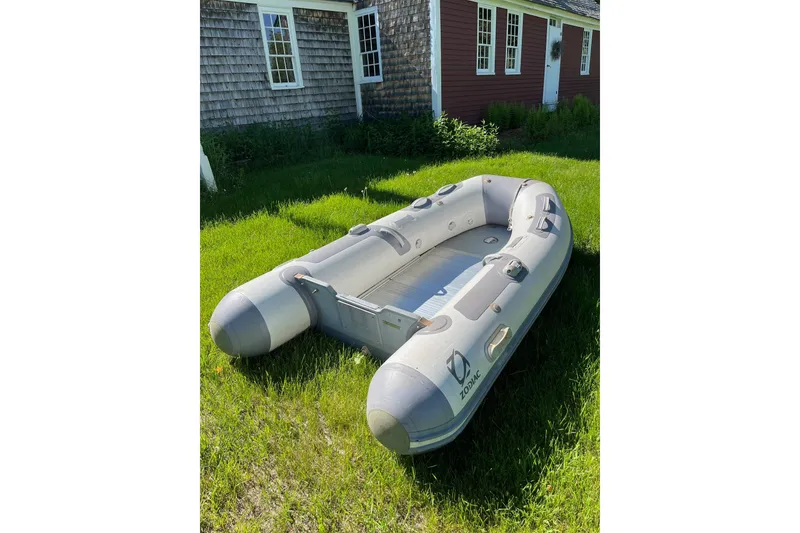 Slide: The Image of Gray inflatable Zodiac boat on grass beside rustic house, sunny day. - 11