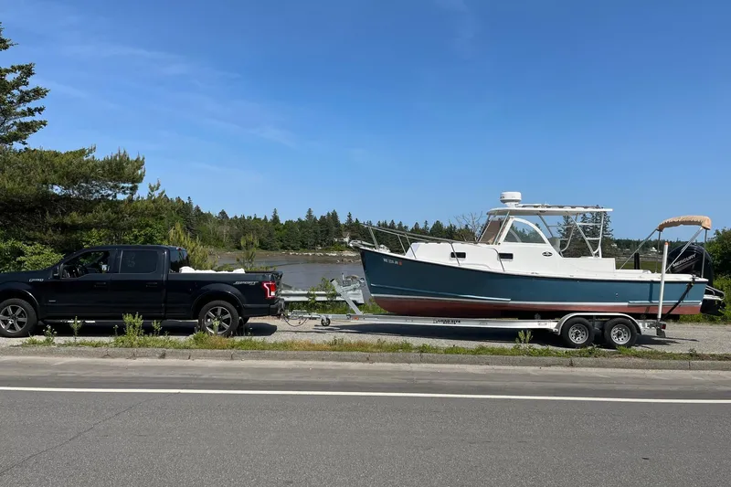 Slide: The Image of Black truck towing a 2014 Seaway 24 Seafarer boat on a trailer by a scenic river. - 14