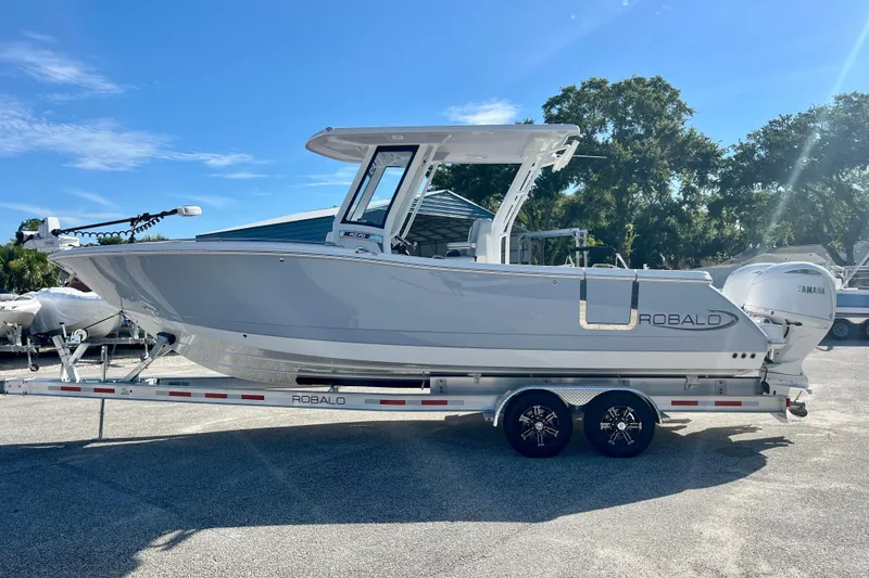 The Image of 2026 Robalo R270 Center Console boat on trailer under clear blue sky. - 1