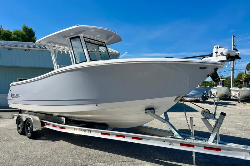 Slide: The Image of 2026 Robalo R270 Center Console boat on trailer, parked outdoors under clear blue sky. - 4
