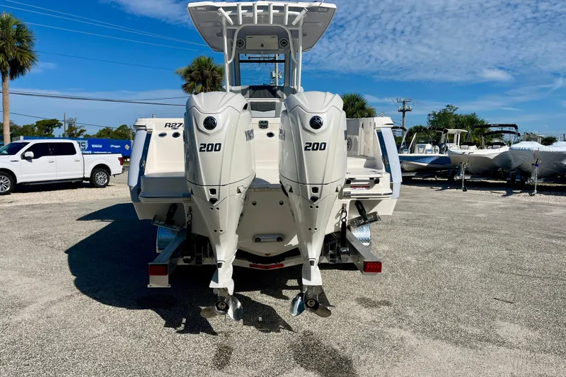 Slide: The Image of 2026 Robalo R270 Center Console boat with dual Yamaha 200 engines, parked outdoors. - 7