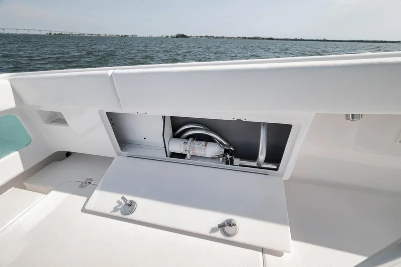 Slide: The Image of Open storage compartment on 2025 Marquesa 34 boat, featuring a fire extinguisher and hose. - 57