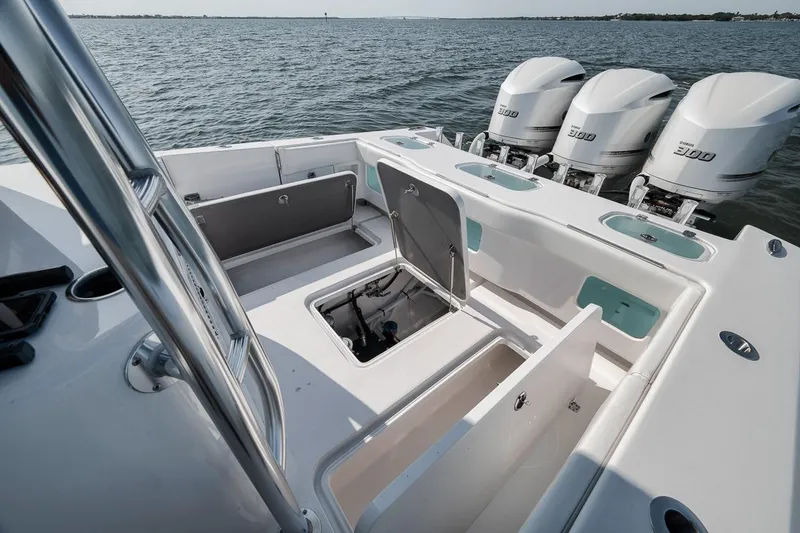 Slide: The Image of 2025 Marquesa 34 boat with open storage compartments and triple outboard engines on the water. - 65