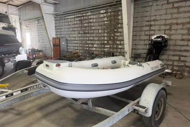 Slide: The Image of A 2026 Desner CL340 inflatable boat on a trailer in a garage. - 1