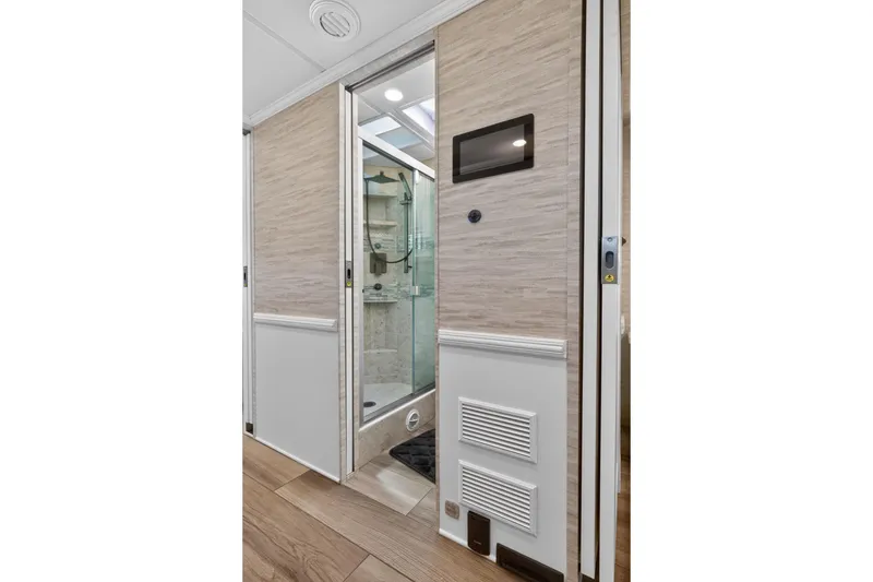 Slide: The Image of 2025 Newmar Dutch Star 4340 RV bathroom with modern shower and sleek wood paneling. - 19