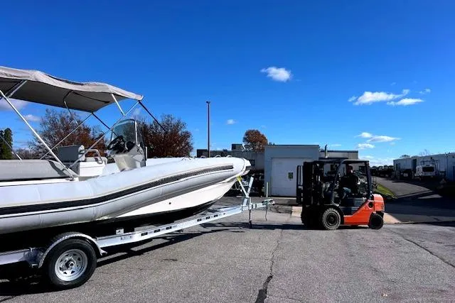 Slide: The Image of 2023 Zodiac N-ZO 680 boat on trailer, moved by forklift under clear blue sky. - 1