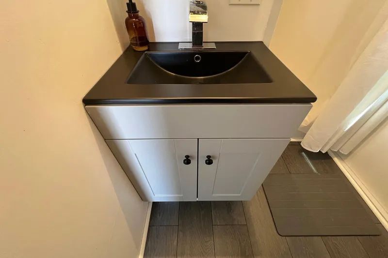 Slide: The Image of Modern bathroom sink with black countertop on a 2019 Catamaran Cruisers houseboat. - 11