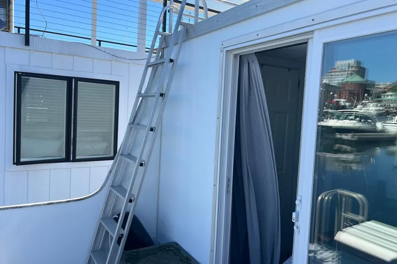 Slide: The Image of 2019 Catamaran Cruisers houseboat with ladder, window, and open door overlooking marina. - 19