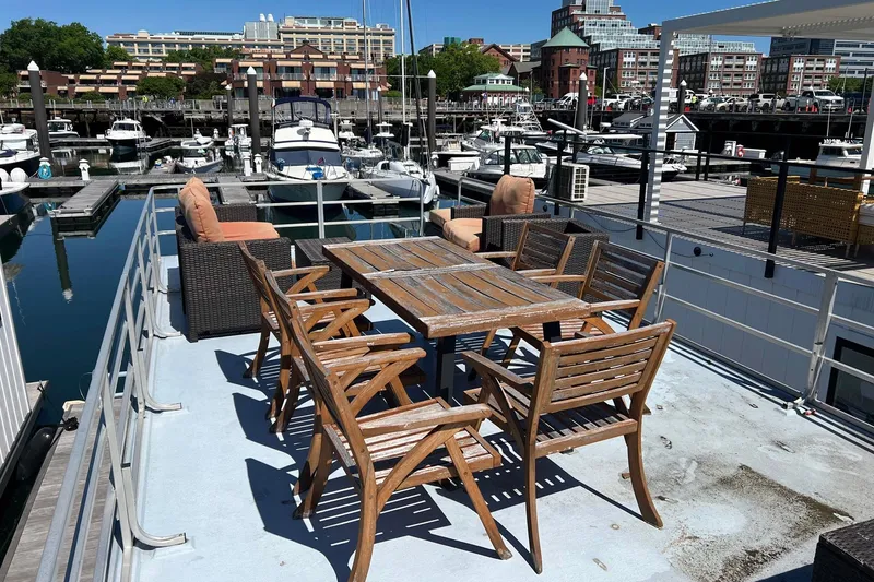 Slide: The Image of 2019 Catamaran Cruisers houseboat with wooden deck furniture, docked in a marina. - 24