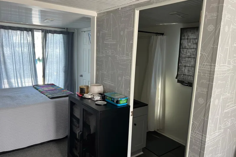 Slide: The Image of Interior of a 2019 Catamaran Cruisers houseboat with bed, curtains, and bathroom. - 25