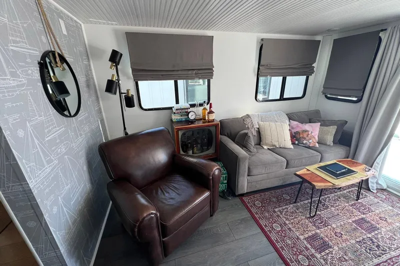 Slide: The Image of Cozy 2019 Catamaran Cruisers houseboat interior with leather chair, sofa, and nautical decor. - 3