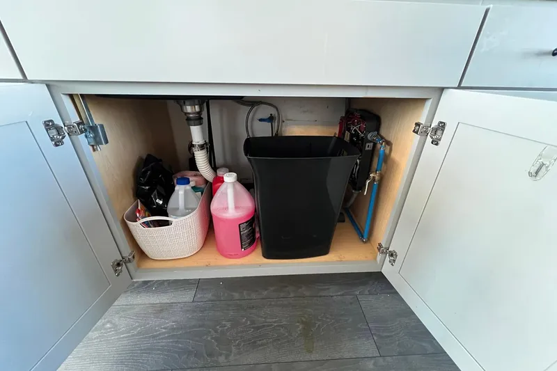 Slide: The Image of Under-sink storage in 2019 Catamaran Cruisers houseboat with cleaning supplies and plumbing. - 7
