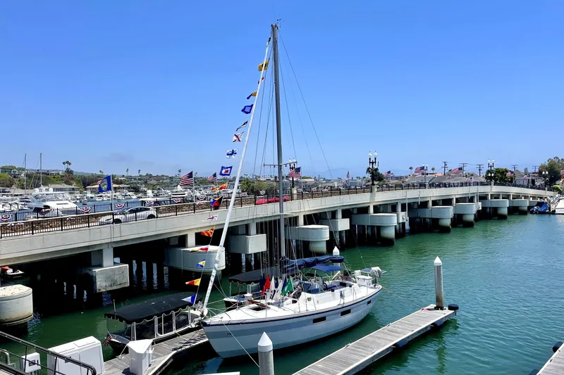 Slide: The Image of 1972 Coronado Yachts 35 Center Cockpit sailboat docked near a bridge on a sunny day. - 1