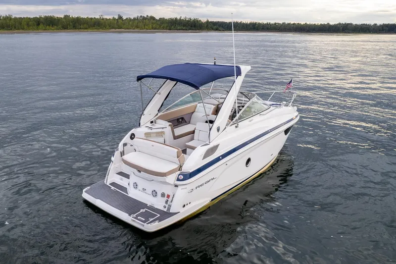 Slide: The Image of 2016 Regal 28 Express boat on calm water with blue canopy. - 1