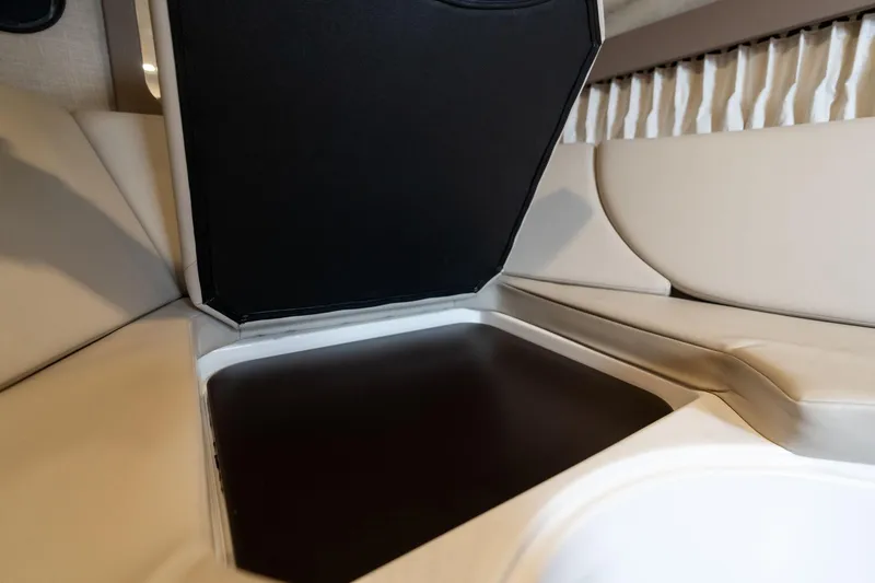 Slide: The Image of 2016 Regal 28 Express interior storage compartment with beige seating and black lid. - 11