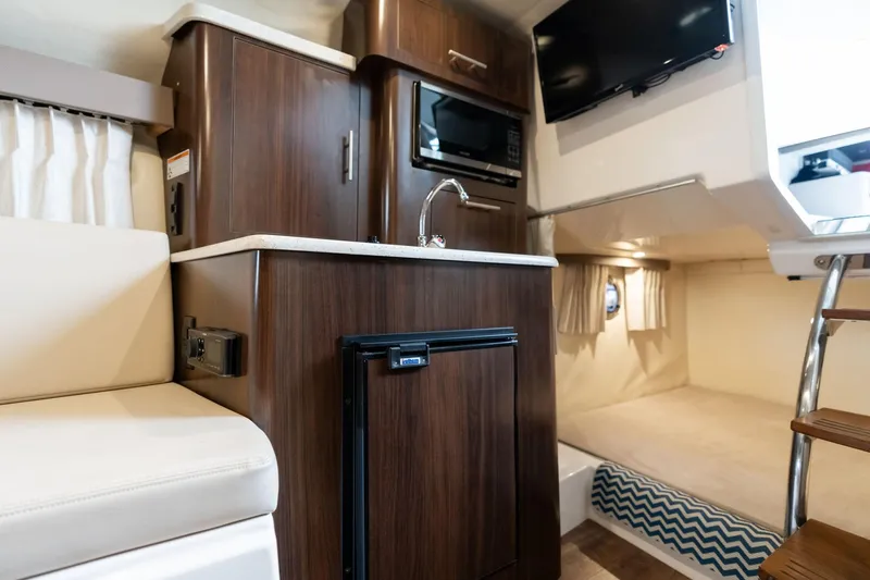 Slide: The Image of 2016 Regal 28 Express cabin interior with kitchenette, bed, and TV. - 14