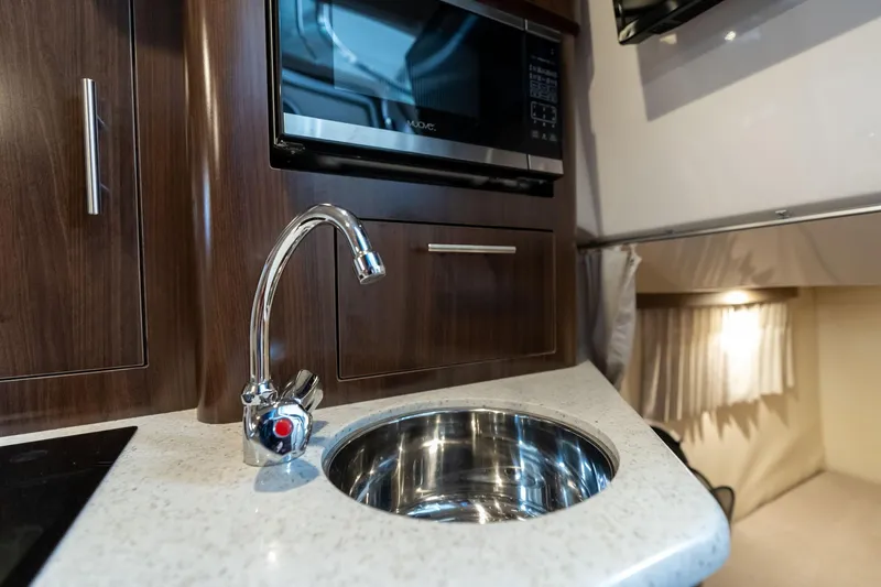 Slide: The Image of Compact kitchen area in a 2016 Regal 28 Express boat with sink and microwave. - 16