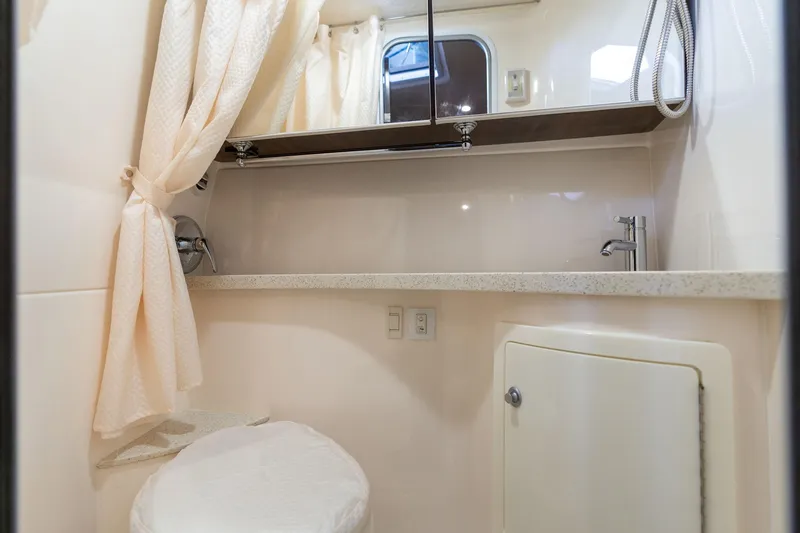 Slide: The Image of 2016 Regal 28 Express boat bathroom with sink, mirror, and shower curtain. - 22
