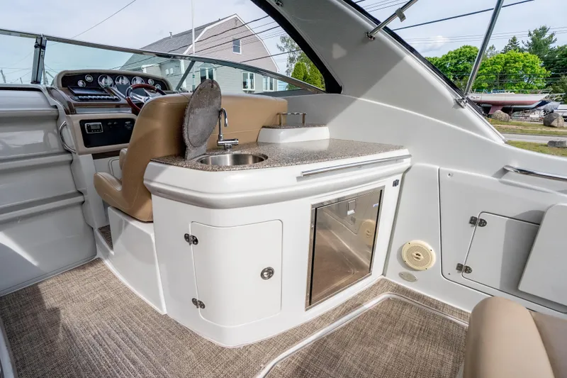 Slide: The Image of 2015 Crownline 294 CR boat interior with helm, sink, and storage cabinets. - 11