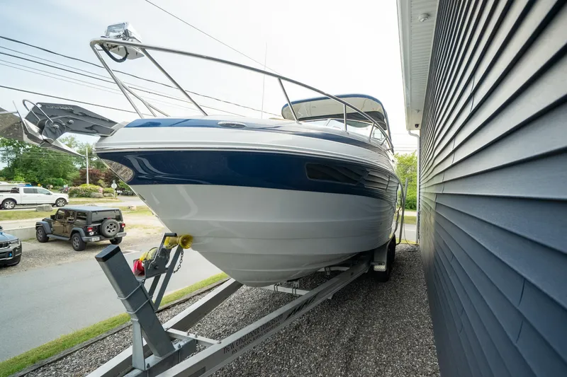 Slide: The Image of 2015 Crownline 294 CR boat on trailer beside building, showcasing sleek design. - 3
