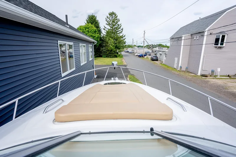 Slide: The Image of 2015 Crownline 294 CR boat with beige sunpad, docked near buildings. - 15