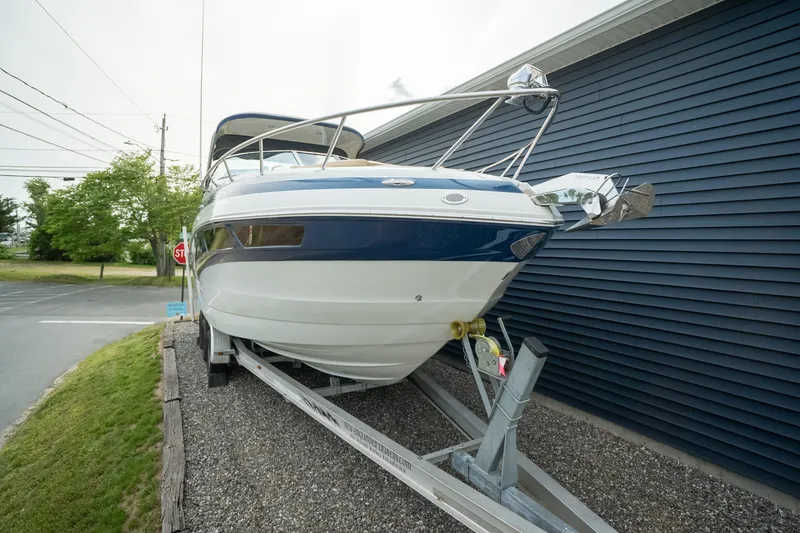 Slide: The Image of 2015 Crownline 294 CR boat on trailer beside blue building. - 2