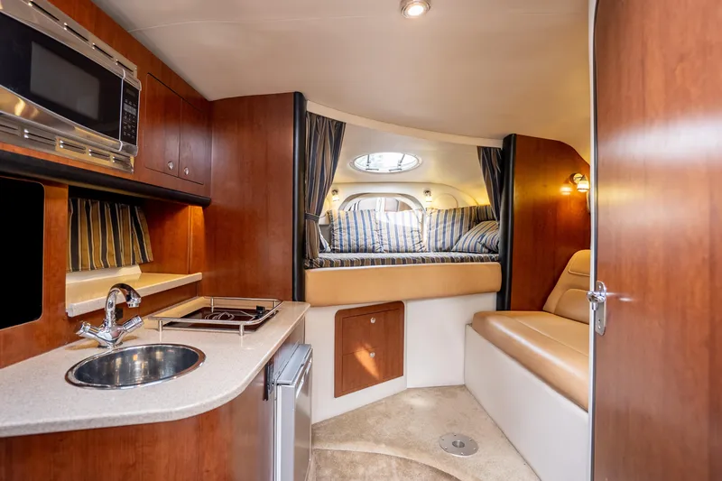 Slide: The Image of 2015 Crownline 294 CR cabin interior with kitchenette, bed, and seating area. - 18