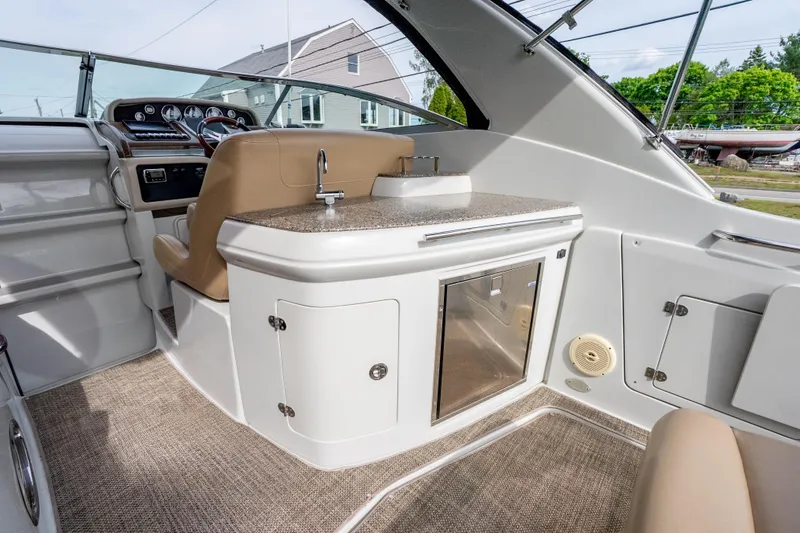 Slide: The Image of 2015 Crownline 294 CR boat interior with helm, seating, and kitchenette area. - 10