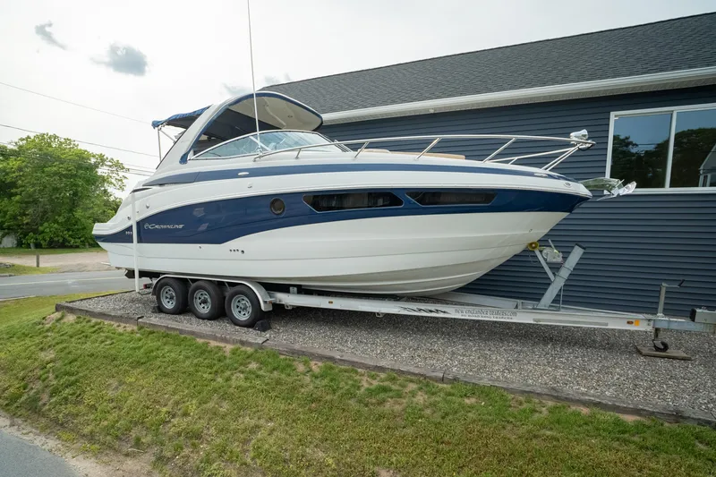 The Image of 2015 Crownline 294 CR boat on trailer, parked beside a building. - 1