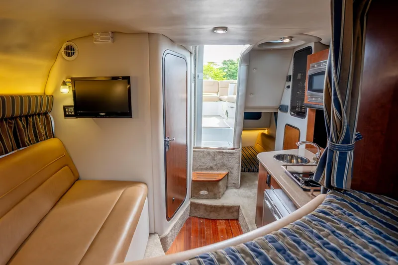 Slide: The Image of Interior of 2015 Crownline 294 CR boat with cozy seating, kitchenette, and TV. - 21