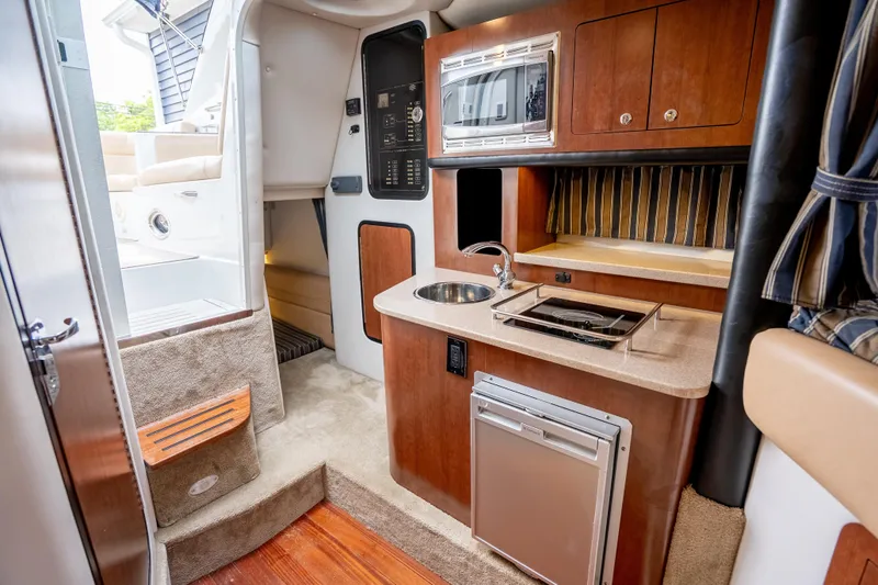 Slide: The Image of 2015 Crownline 294 CR boat interior with kitchenette and seating area. - 16