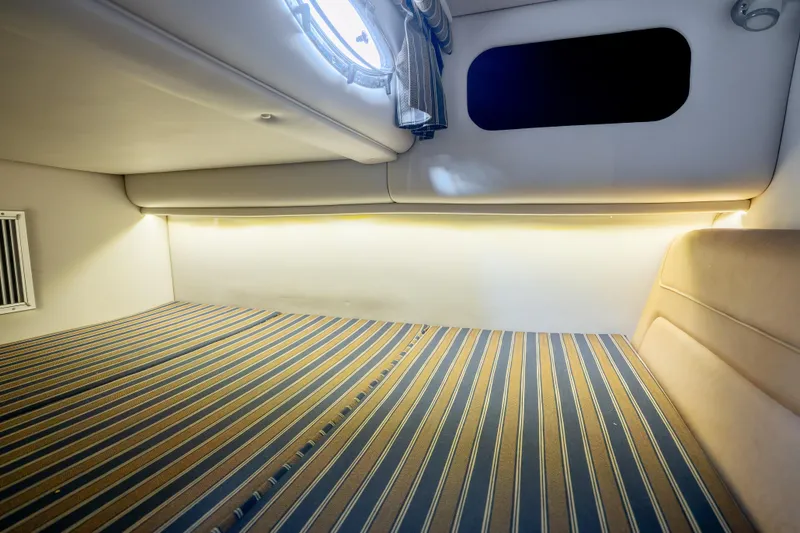 Slide: The Image of Interior cabin of 2015 Crownline 294 CR boat with striped bedding and ambient lighting. - 20