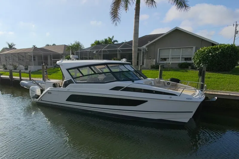 The Image of 2019 Aquila 36 Sport boat docked by a waterfront home with palm trees. - 0