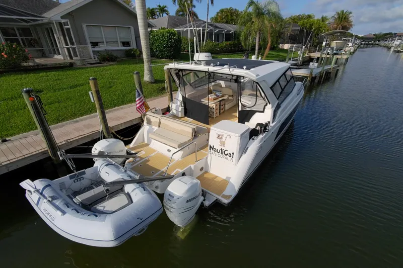 Slide: The Image of Aquila 36 Sport 2019 docked, featuring dual outboard engines and a small inflatable boat. - 14