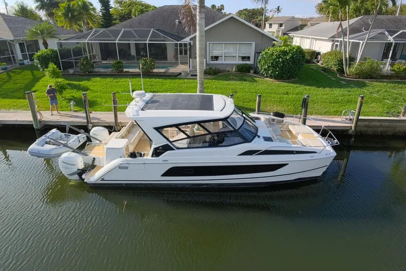Slide: The Image of 2019 Aquila 36 Sport yacht docked by waterfront homes, featuring sleek design and modern amenities. - 3