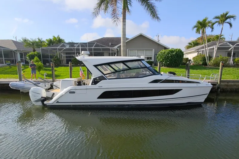 Slide: The Image of 2019 Aquila 36 Sport boat docked by waterfront homes with palm trees. - 4